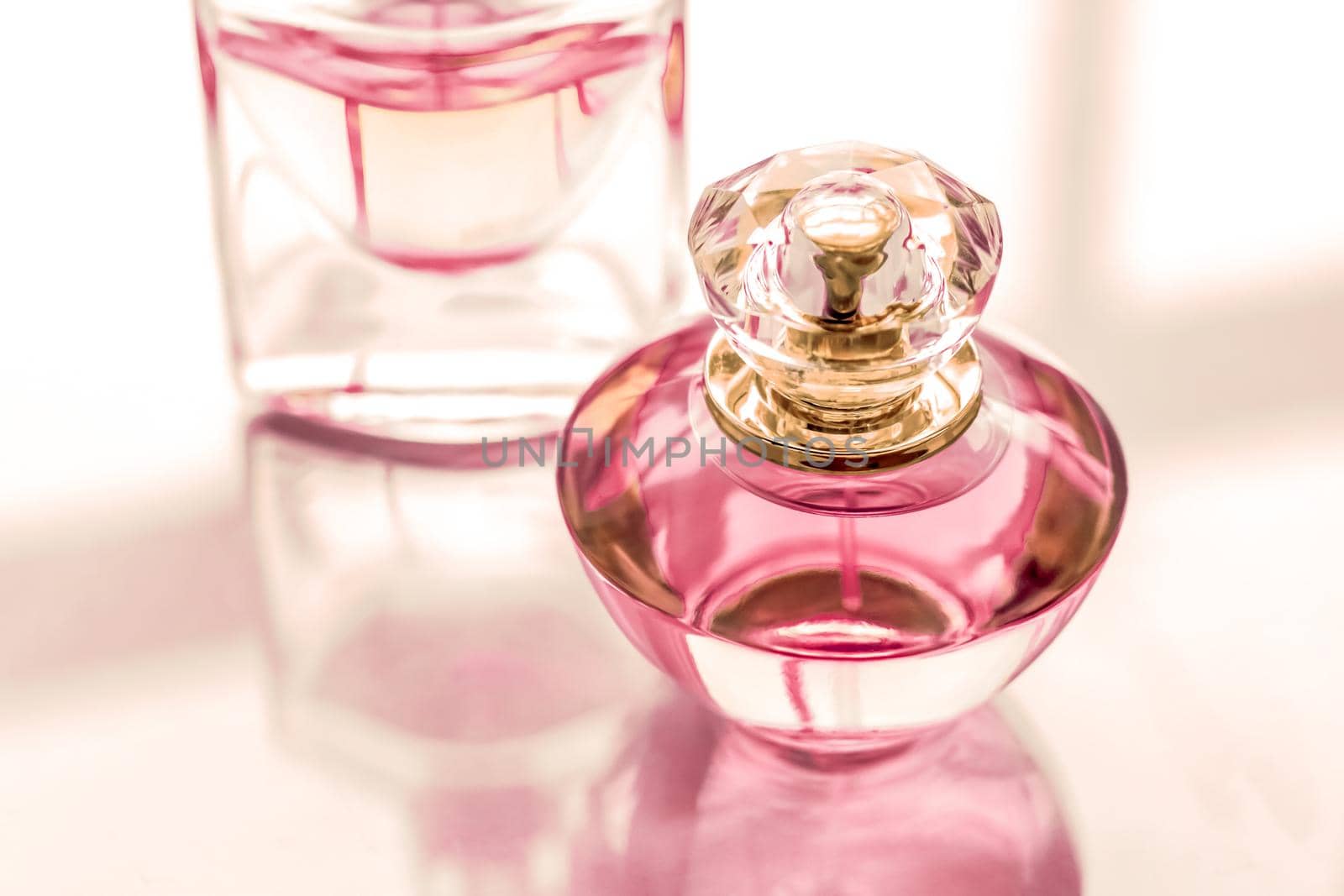 Perfumery, spa and branding concept - Pink perfume bottle on glossy background, sweet floral scent, glamour fragrance and eau de parfum as holiday gift and luxury beauty cosmetics brand design