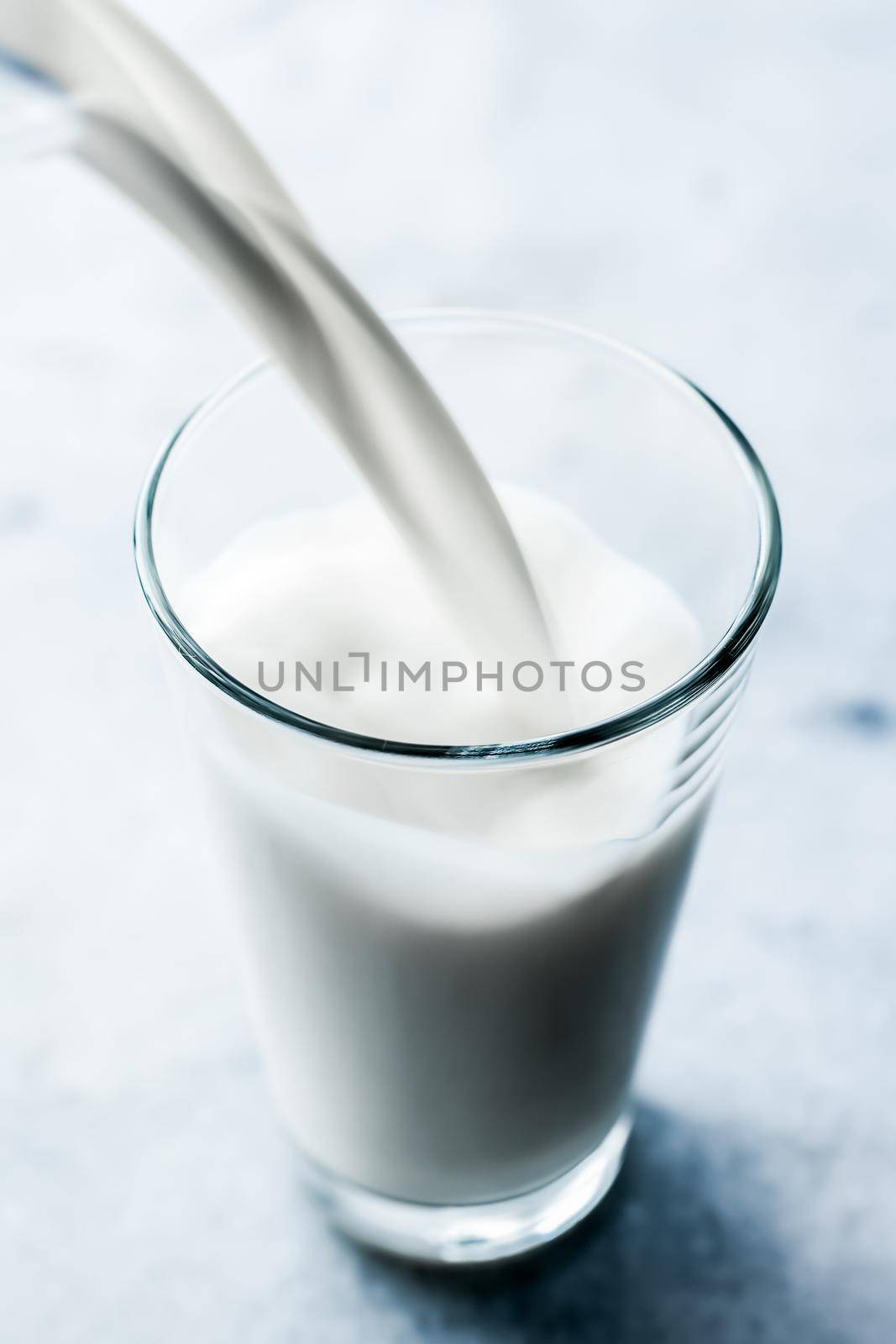 Dairy, healthy nutrition and breakfast concept - World Milk Day, pouring into glass on marble table