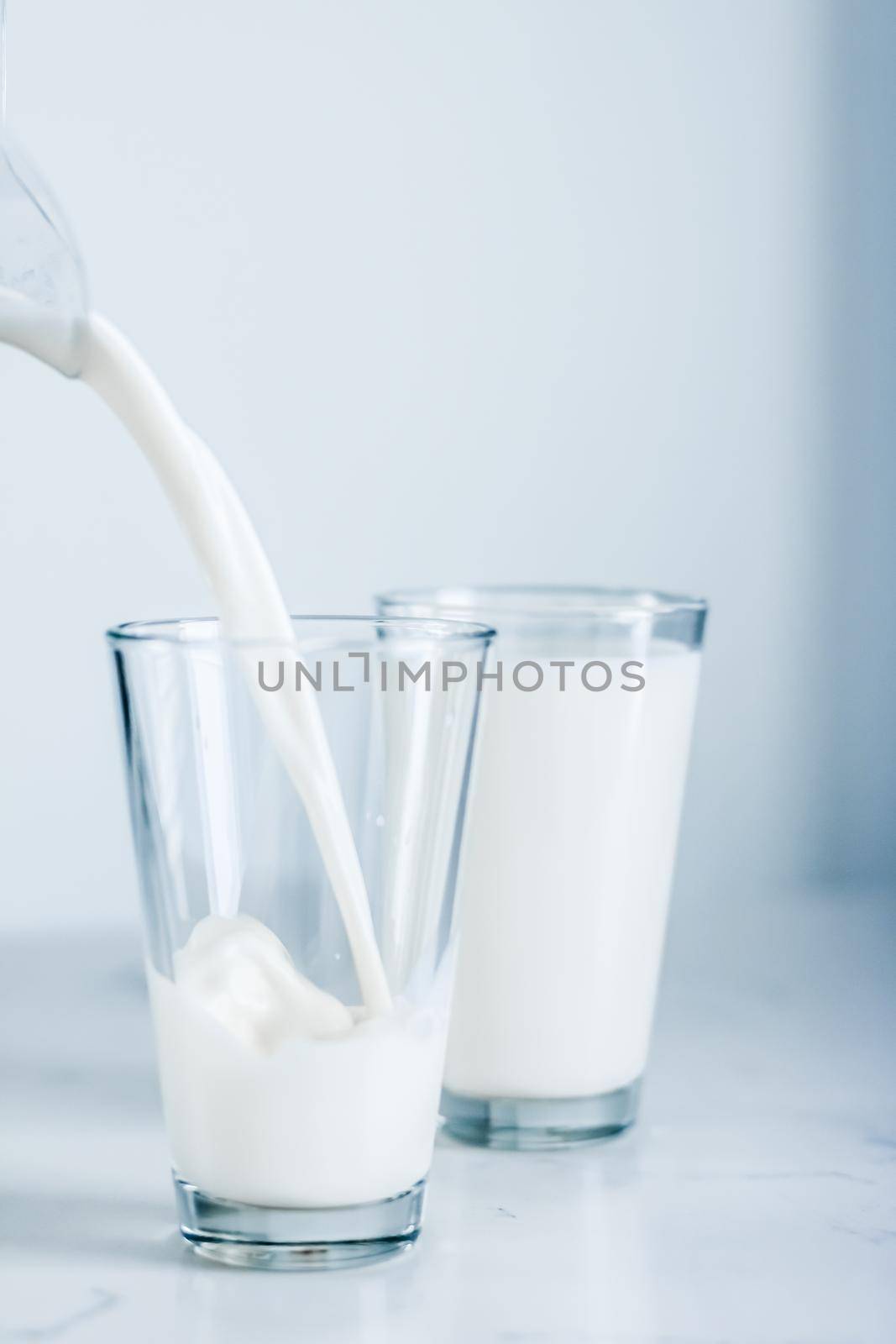 Dairy, healthy nutrition and breakfast concept - World Milk Day, pouring into glass on marble table