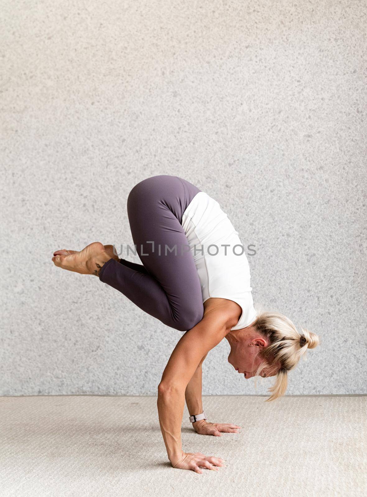 Active lifestyle. Young attractive woman wearing sportswear practicing yoga at home. Indoor full length, gray background