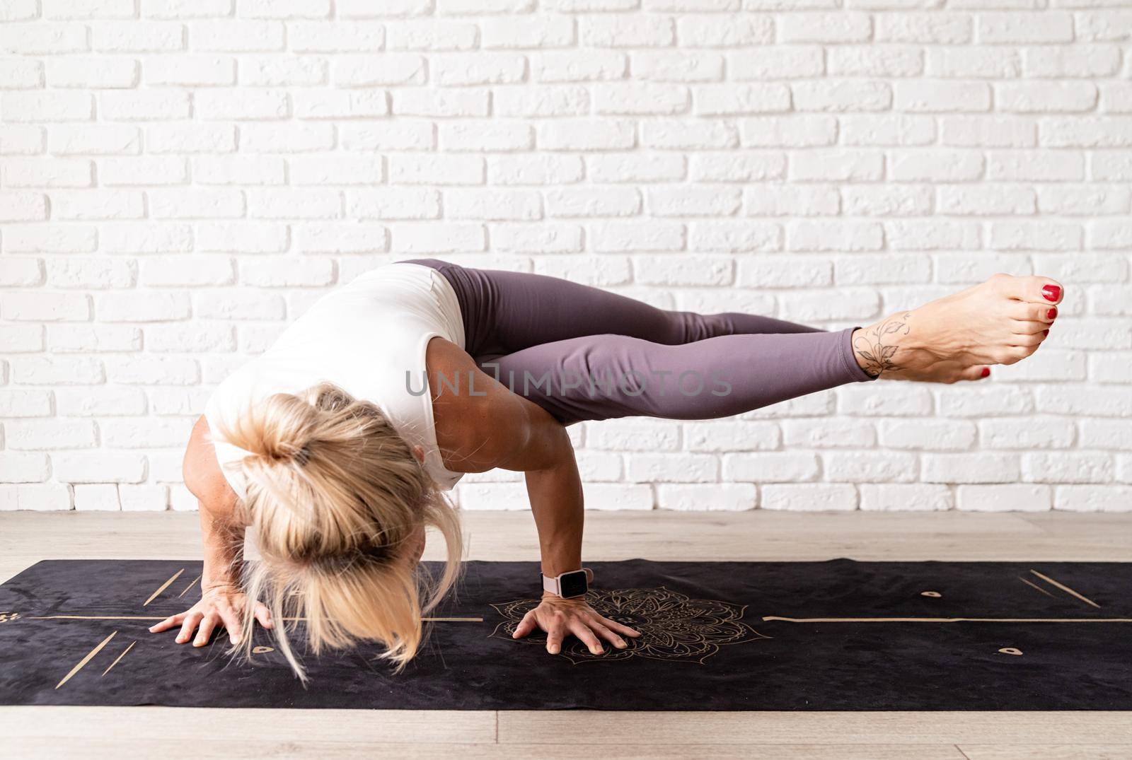 Active lifestyle. Young attractive woman wearing sportswear practicing yoga at home. Indoor full length, white brick wall background