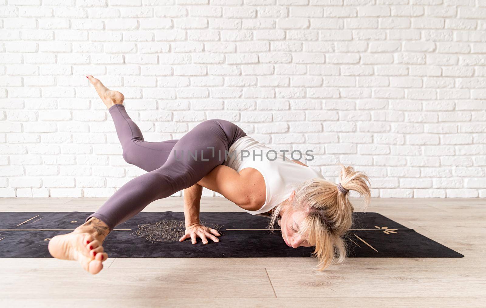 Blond woman practising yoga at home by Desperada