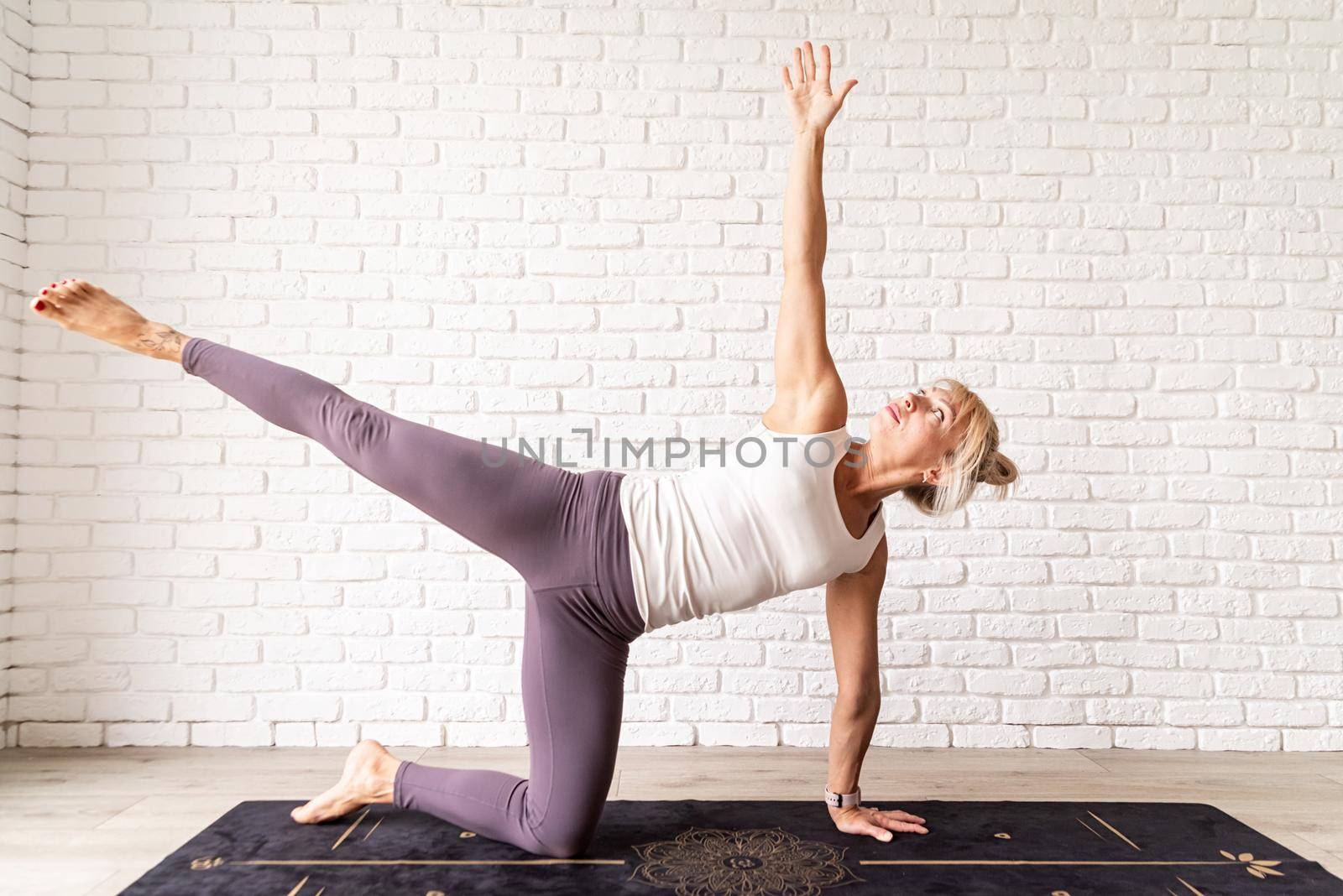 Blond woman practising yoga at home by Desperada