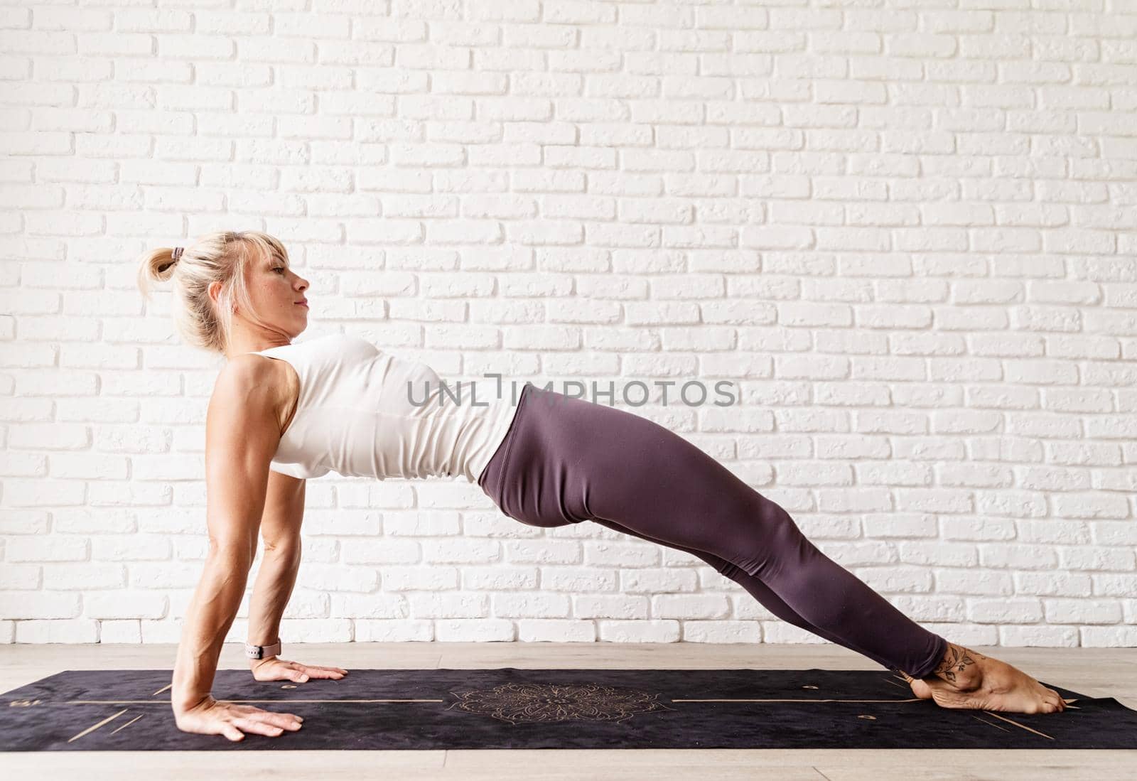 Active lifestyle. Young attractive woman wearing sportswear practicing yoga at home. Indoor full length, white brick wall background