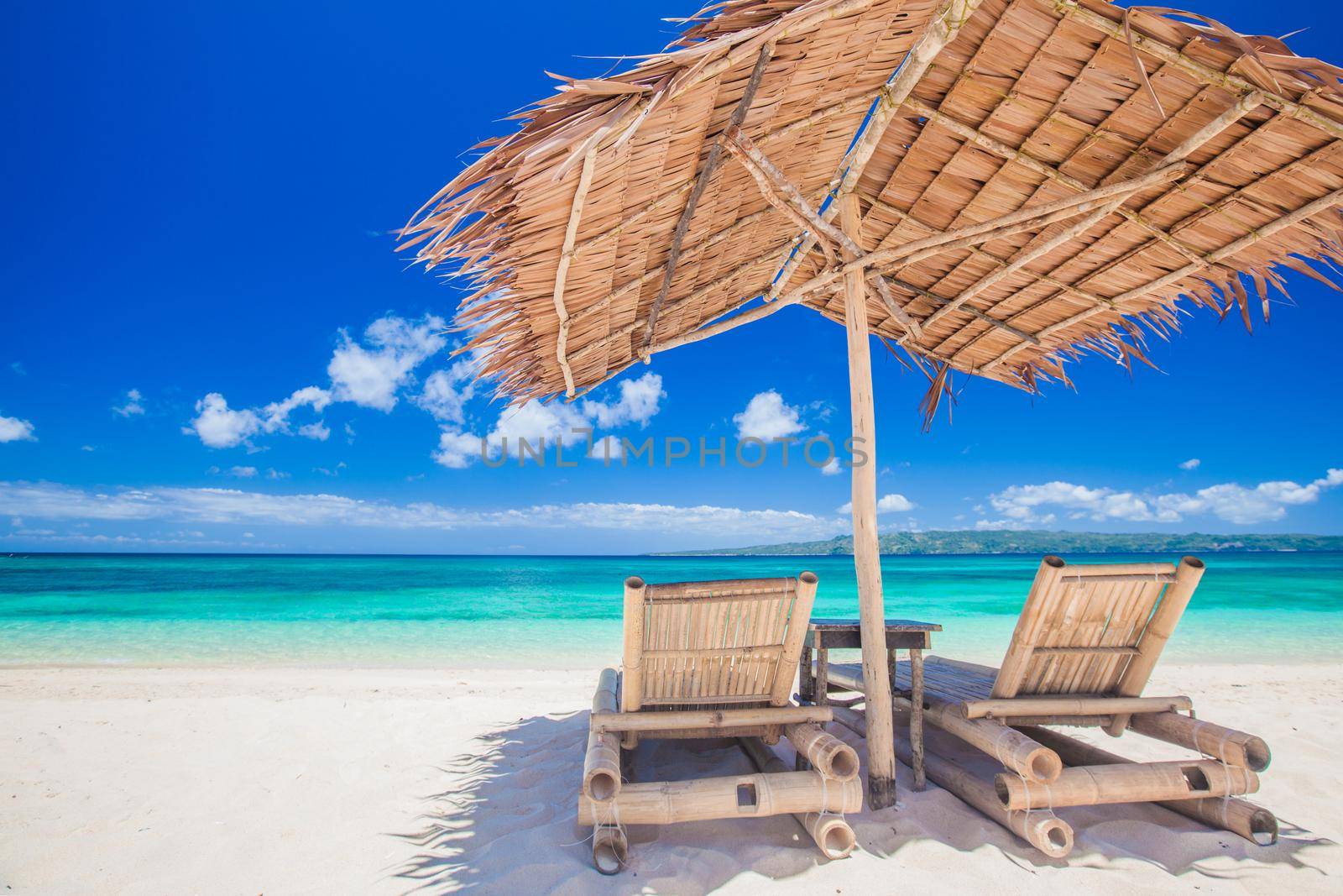 Beach chairs and umbrella on a beautiful tropical sea beach, view with copy space