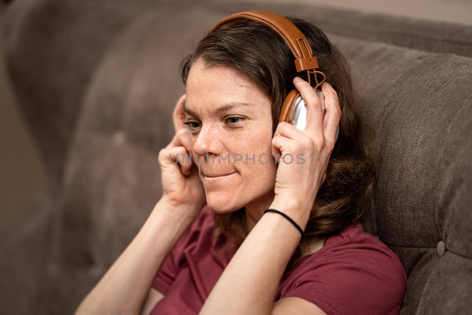 young woman with wireless headphones on her head on the couch.