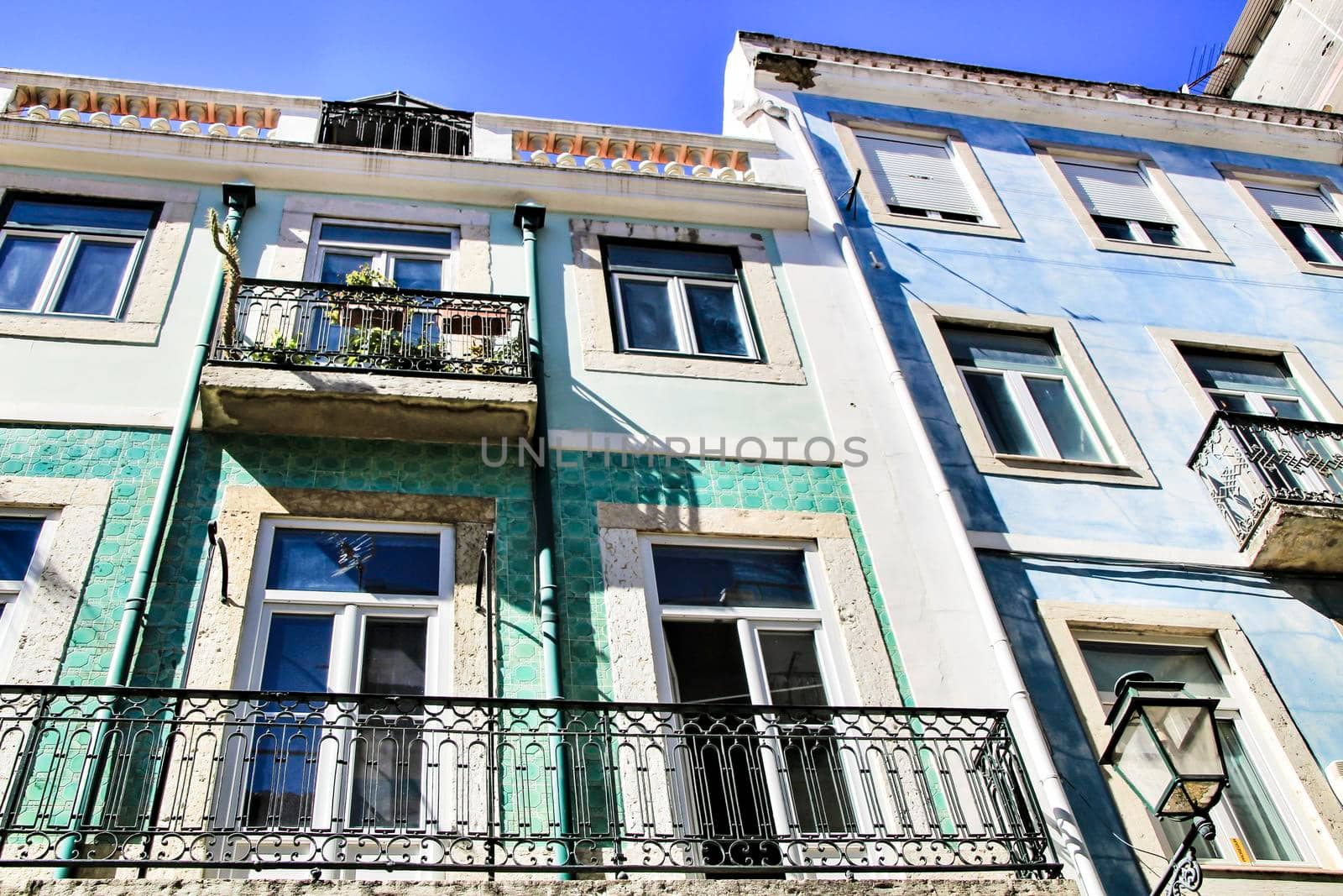 Old colorful and majestic tiled facades with vintage streetlight in Lisbon streets in Spring.