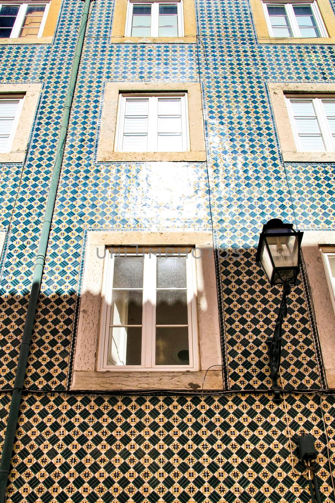 Old colorful and majestic tiled facades with vintage streetlight in Lisbon streets in Spring.