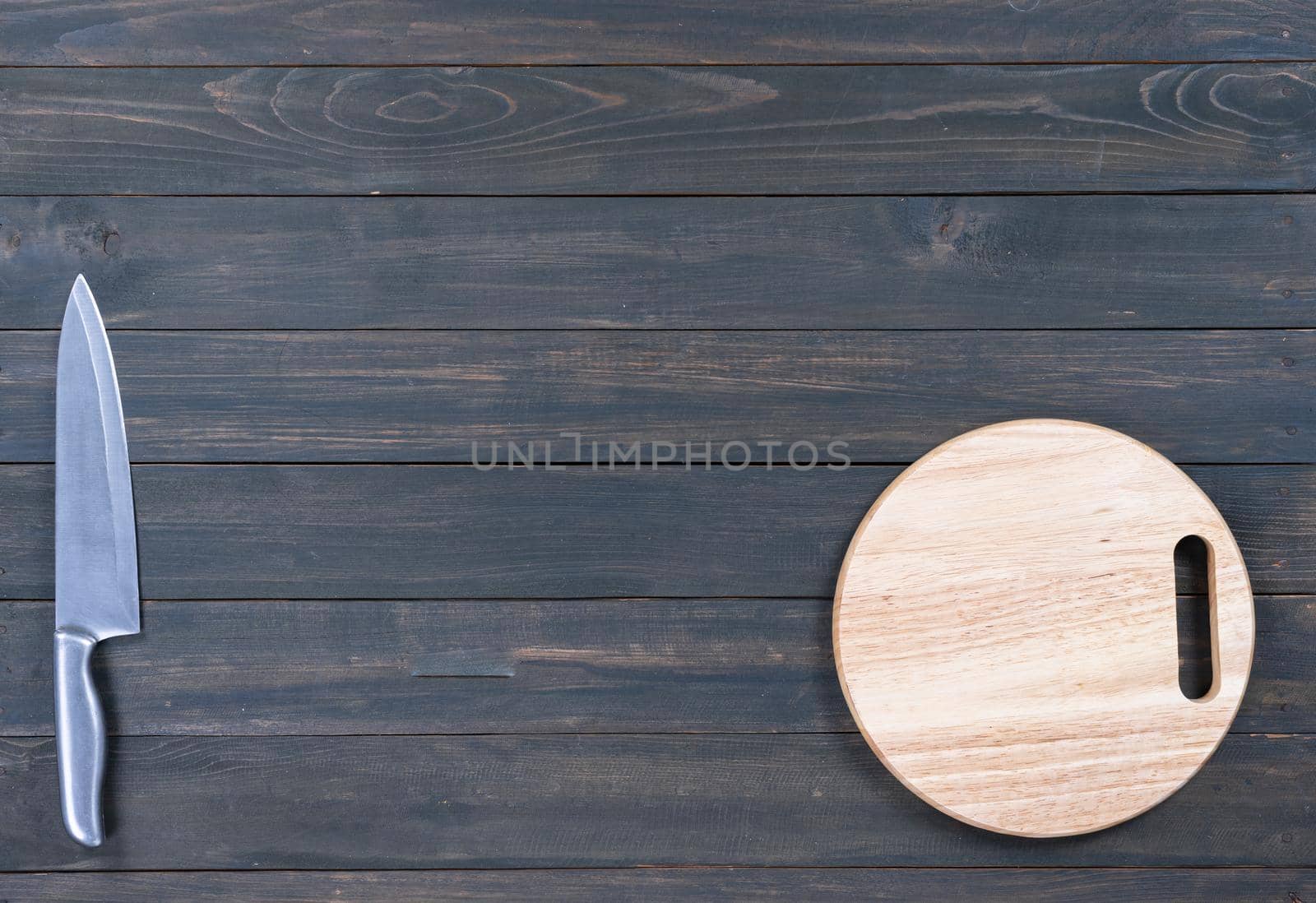 kitchen knife and wooden round empty cutting board on a wooden table close up