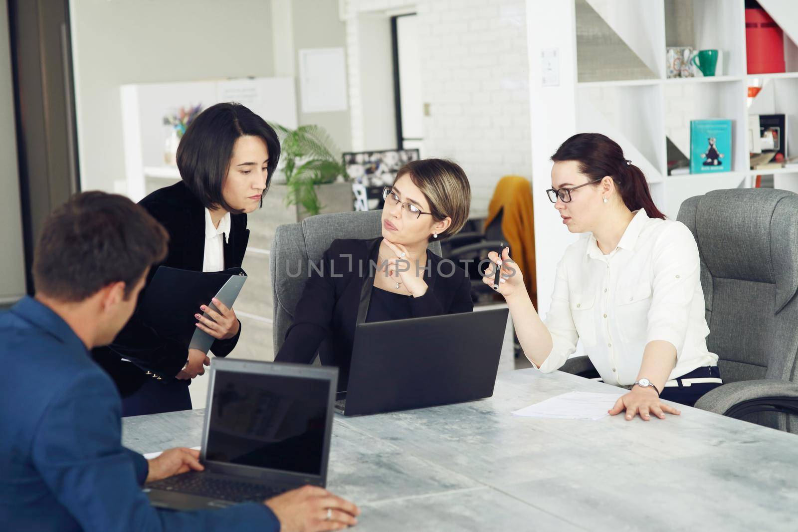 Three young successful business women in the office working together on a project by selinsmo