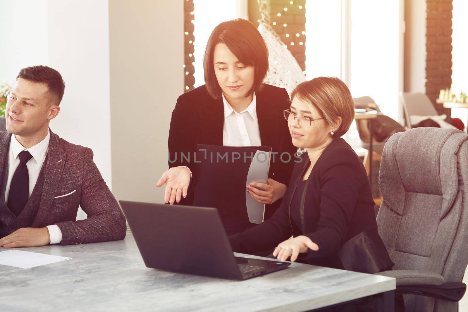 Two young business women in the office, analyzing information looking into a laptop by selinsmo