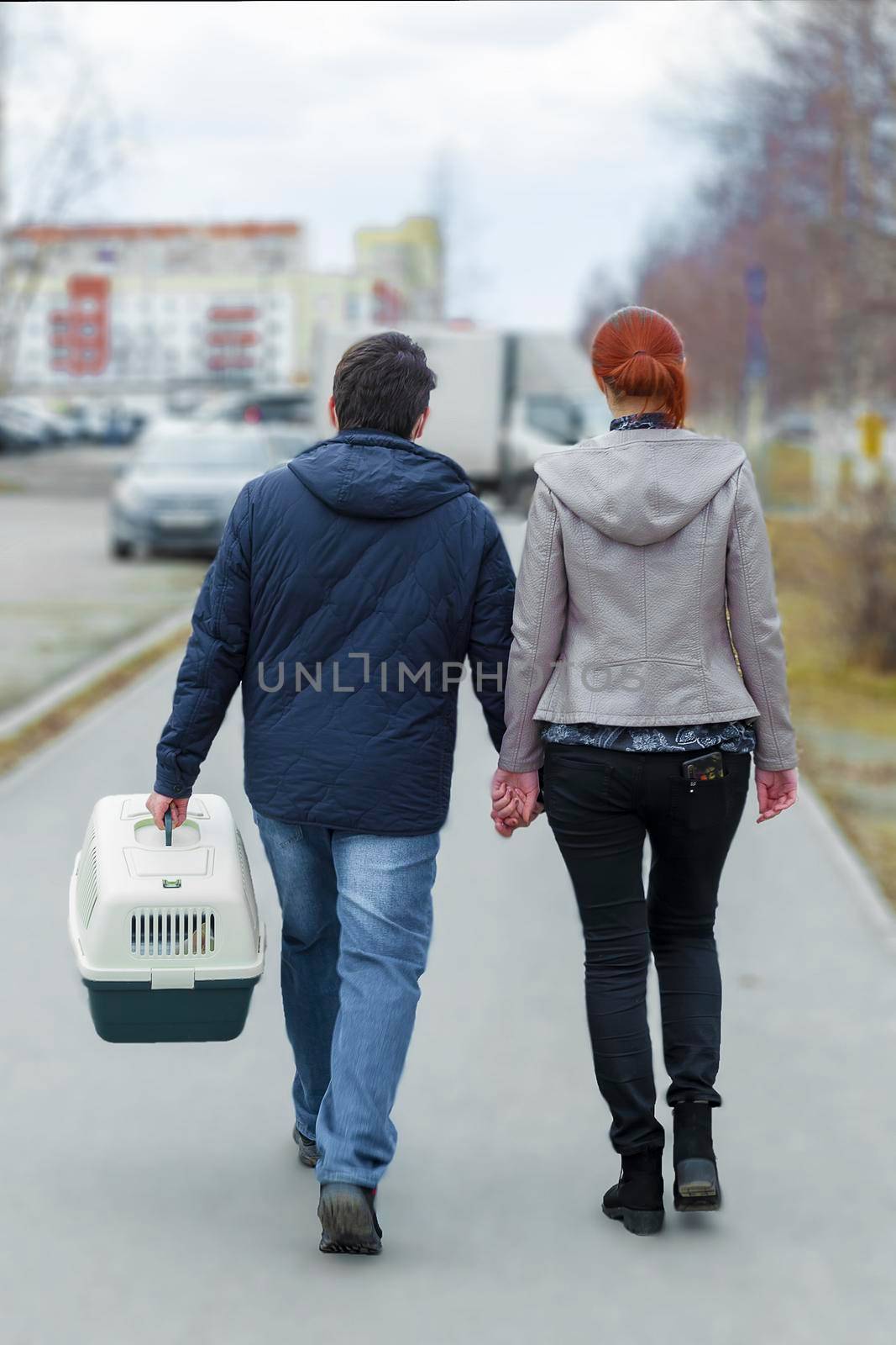 The couple walks and carries the animal in a cage. Surgut, Russia - 16 April 2021 by Essffes
