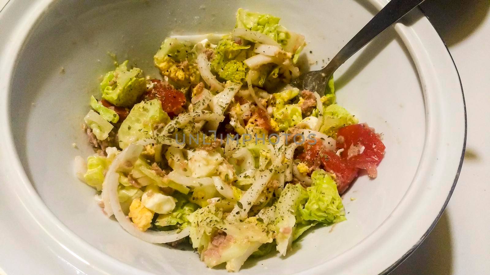 Bowl with salad garnished with oregano in the kitchen