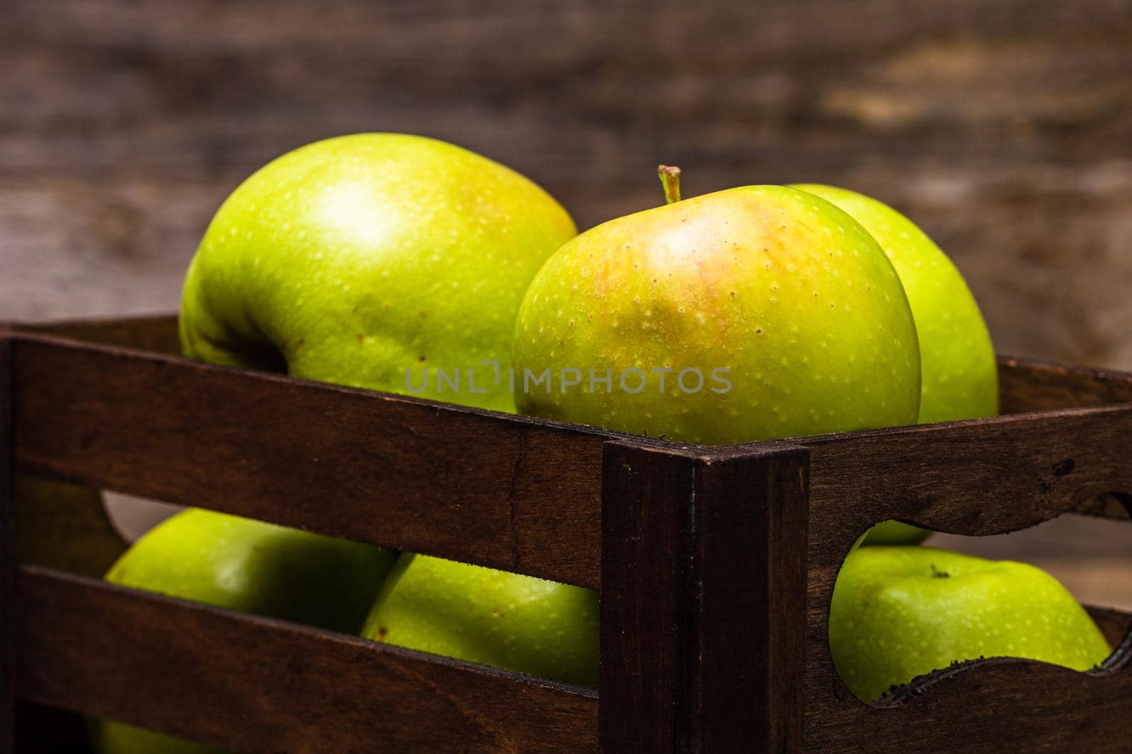 Wooden crate with ripe green apples on wooden table. by vladispas