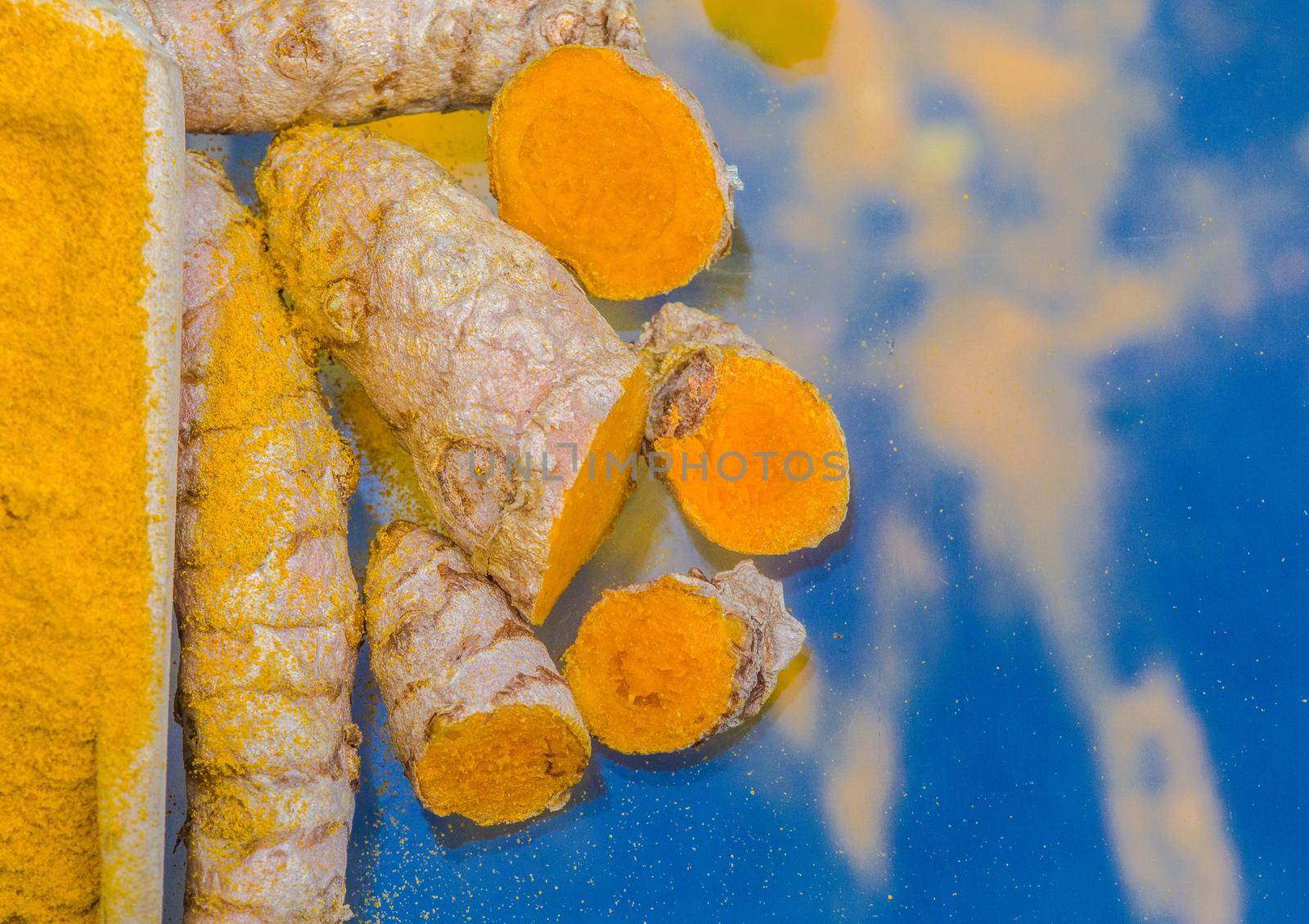 Turmeric powder (Kurkuma) in a wooden spoon and roots  by Weltblick