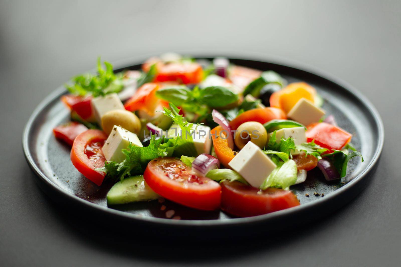 Greek salad on black plate by destillat