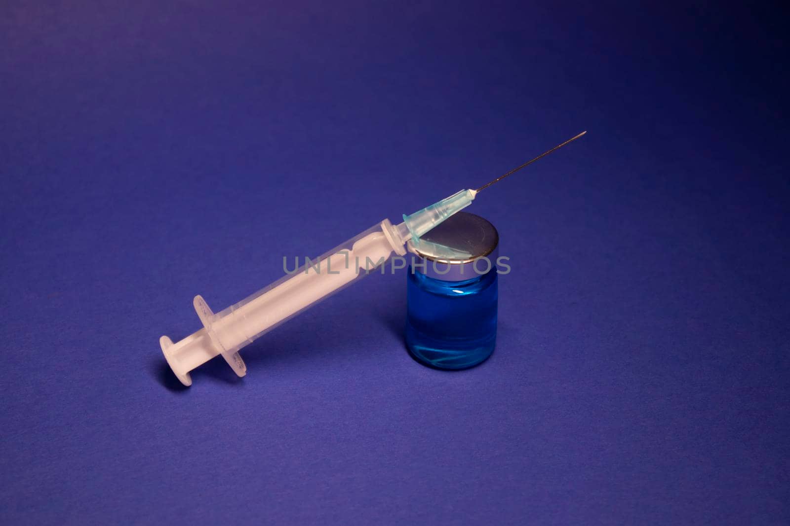 Vaccine bottle phial with no label, medical syringe injection needle. isolated on blue background. Development of coronavirus vaccine COVID-19. cure. World race in researching. copy space