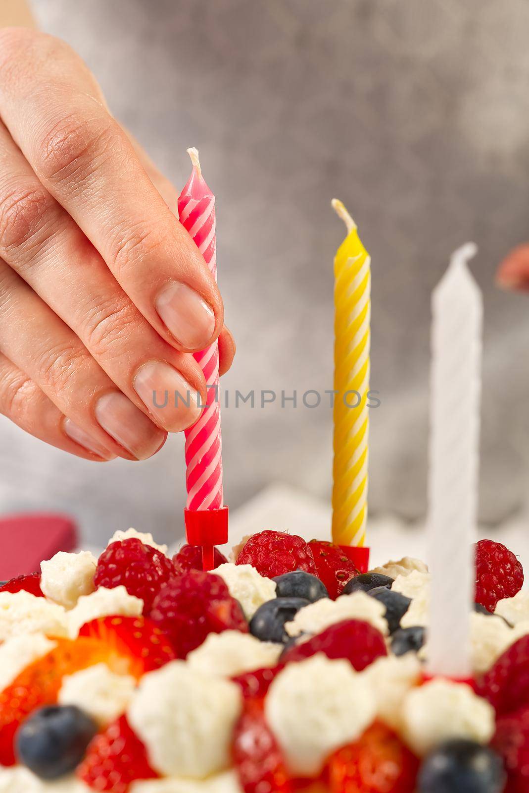 female hand sets birthday candles on homemade strawberry cake. strawberry pie and birthday candles