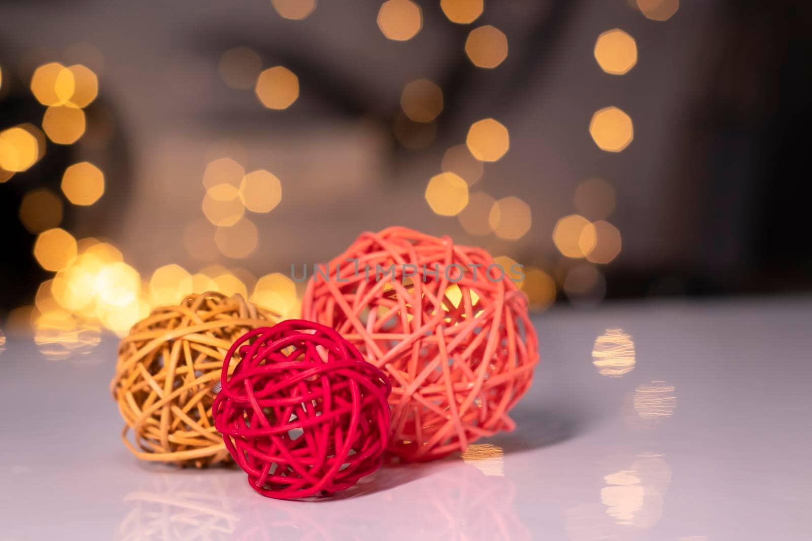 orange, red and pink wicker balls for decoration on a background of golden bokeh.