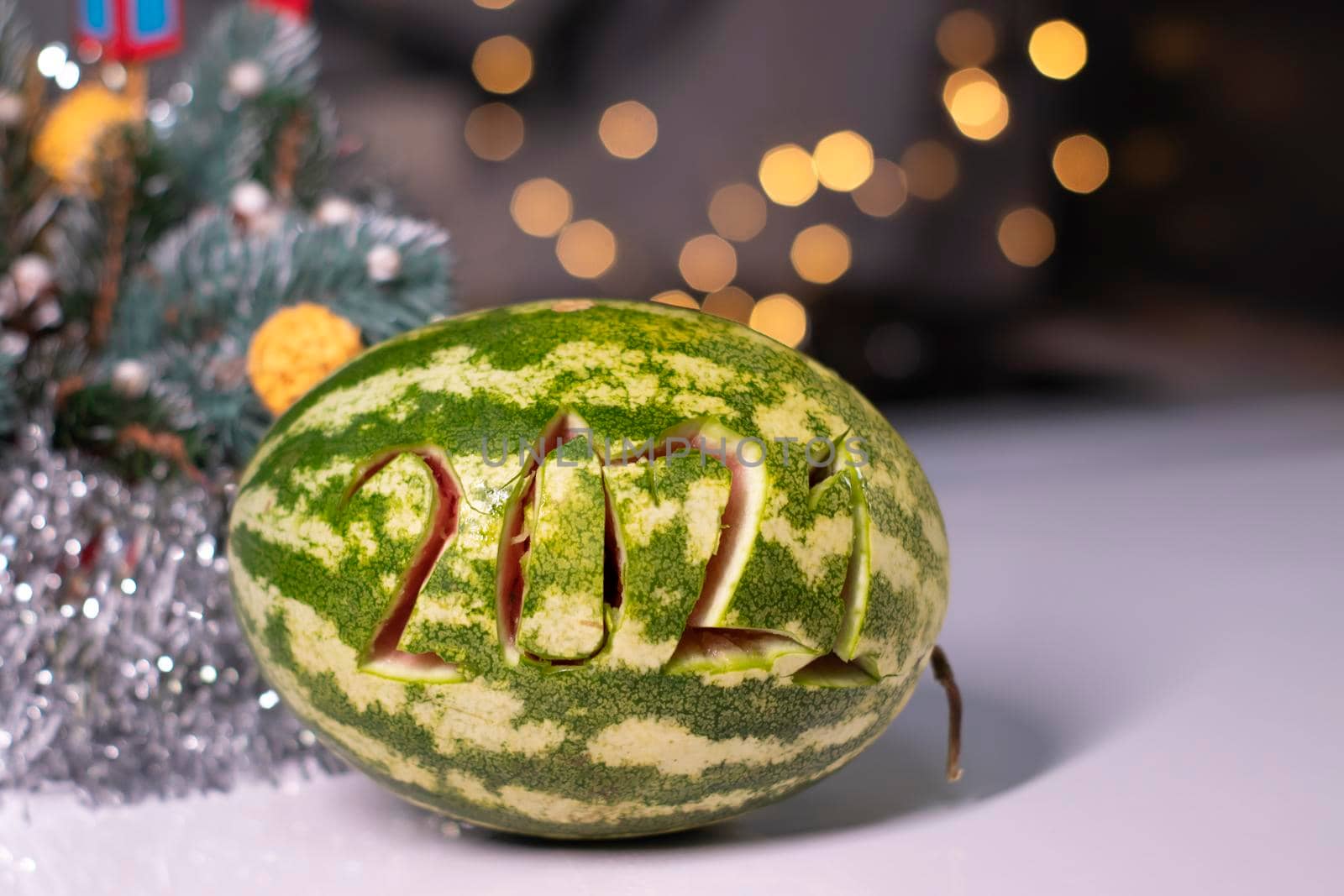 watermelon with 2021 carved number next to new year decorations. christmas theme.