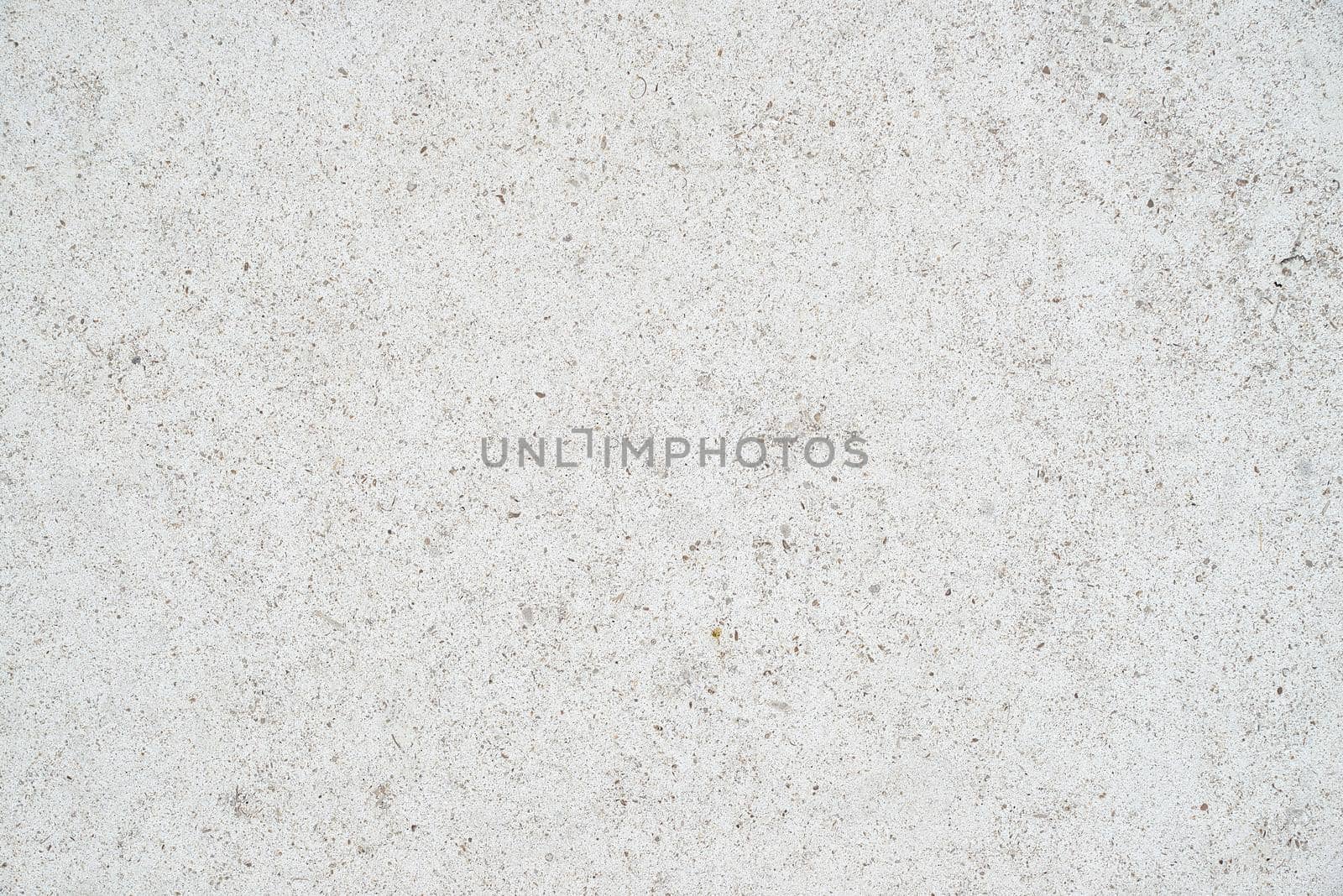 The subtle white textured surface of an external concrete wall. The wall is lightly speckled.