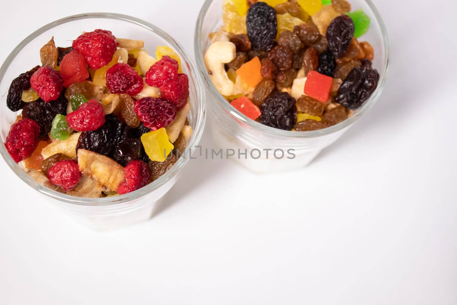 muesli dessert with yogurt and candied or dried fruits with raspberries on top in glass isolated on white background. breakfast Granola