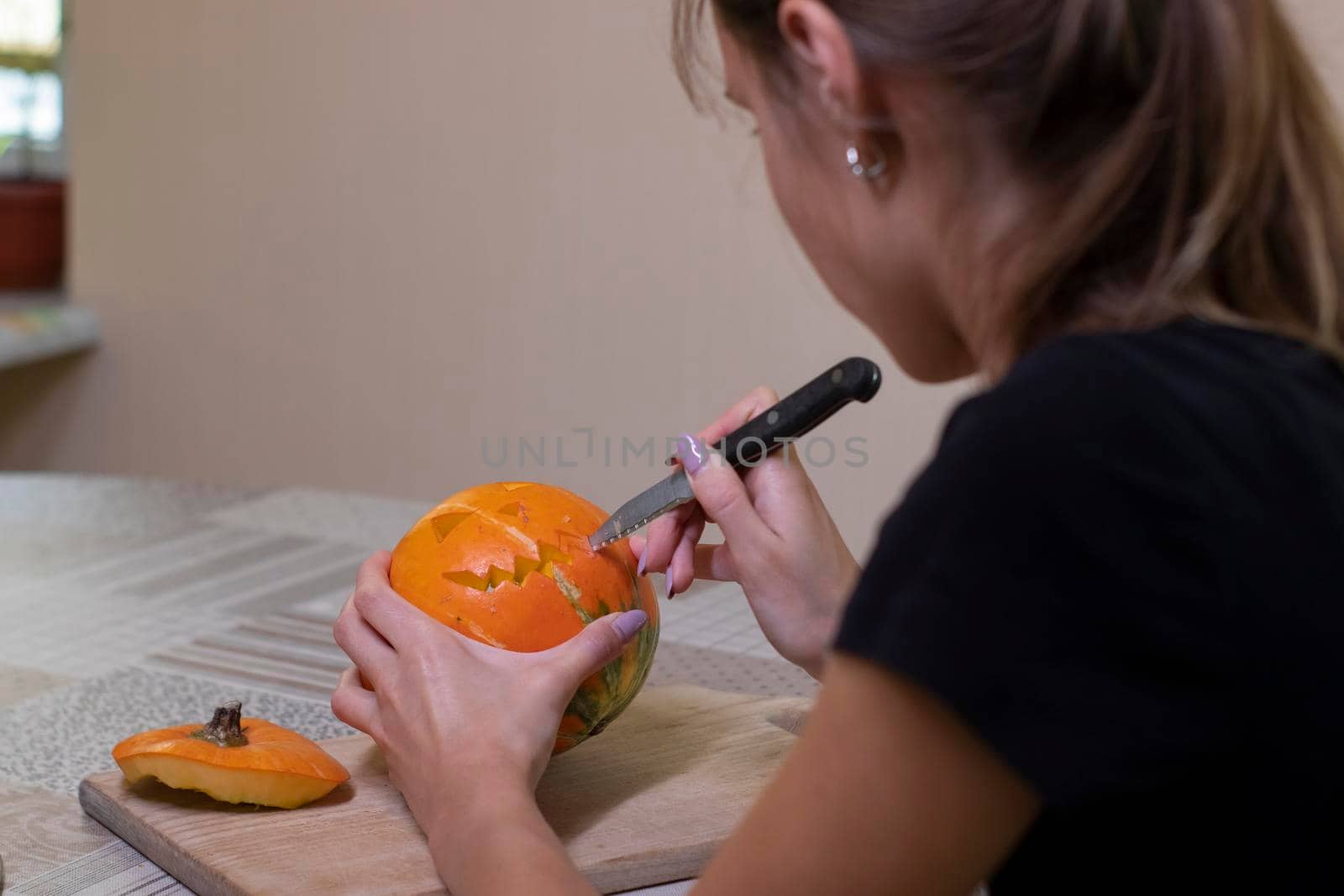 the process of making a Halloween pumpkin. cutting out the mouth by brunette girl. horror theme and Hallowe'en.