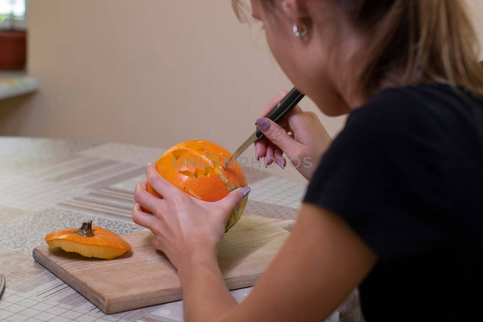 the process of making a Halloween pumpkin. cutting out the mouth by brunette girl. horror theme and Hallowe'en.