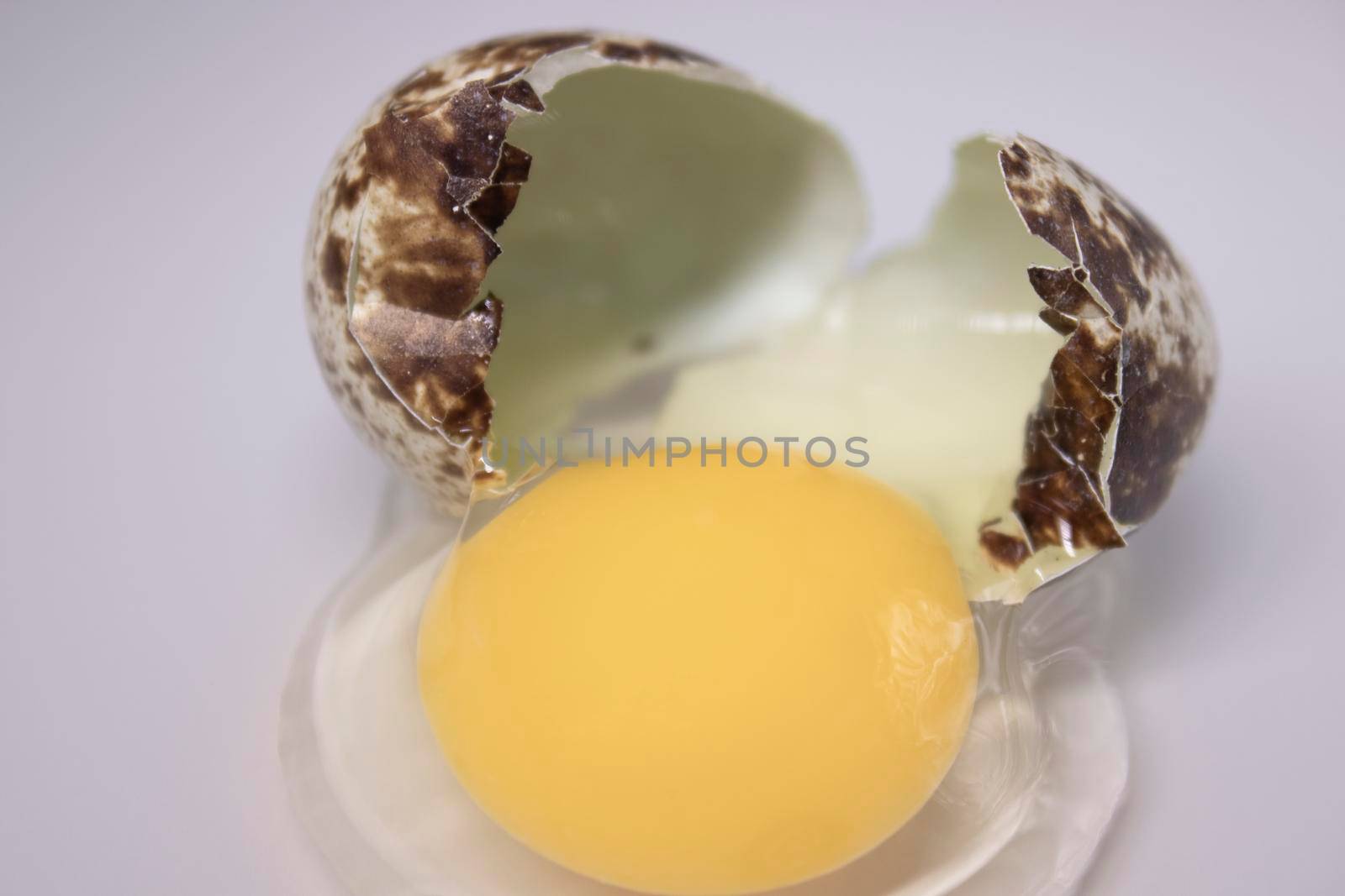 broken Quail egg isolated on white background with leaking white and yolk. healthy raw food.