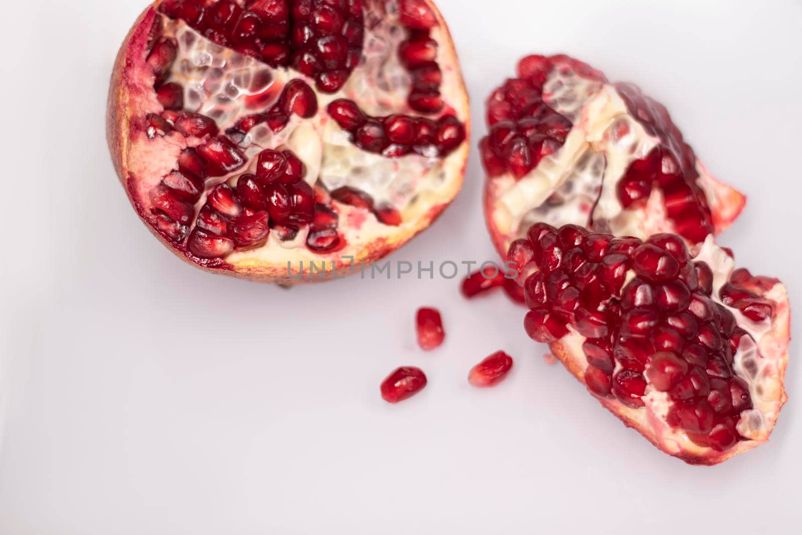 ripe fresh sliced pomegranate fruit with red seeds isolated on white background