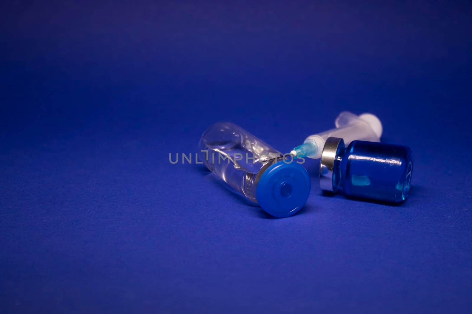 two transparent Vaccine bottle phial with no label, medical syringe injection needle. isolated on blue background. Development of coronavirus vaccine COVID-19. World race in researching. copy space