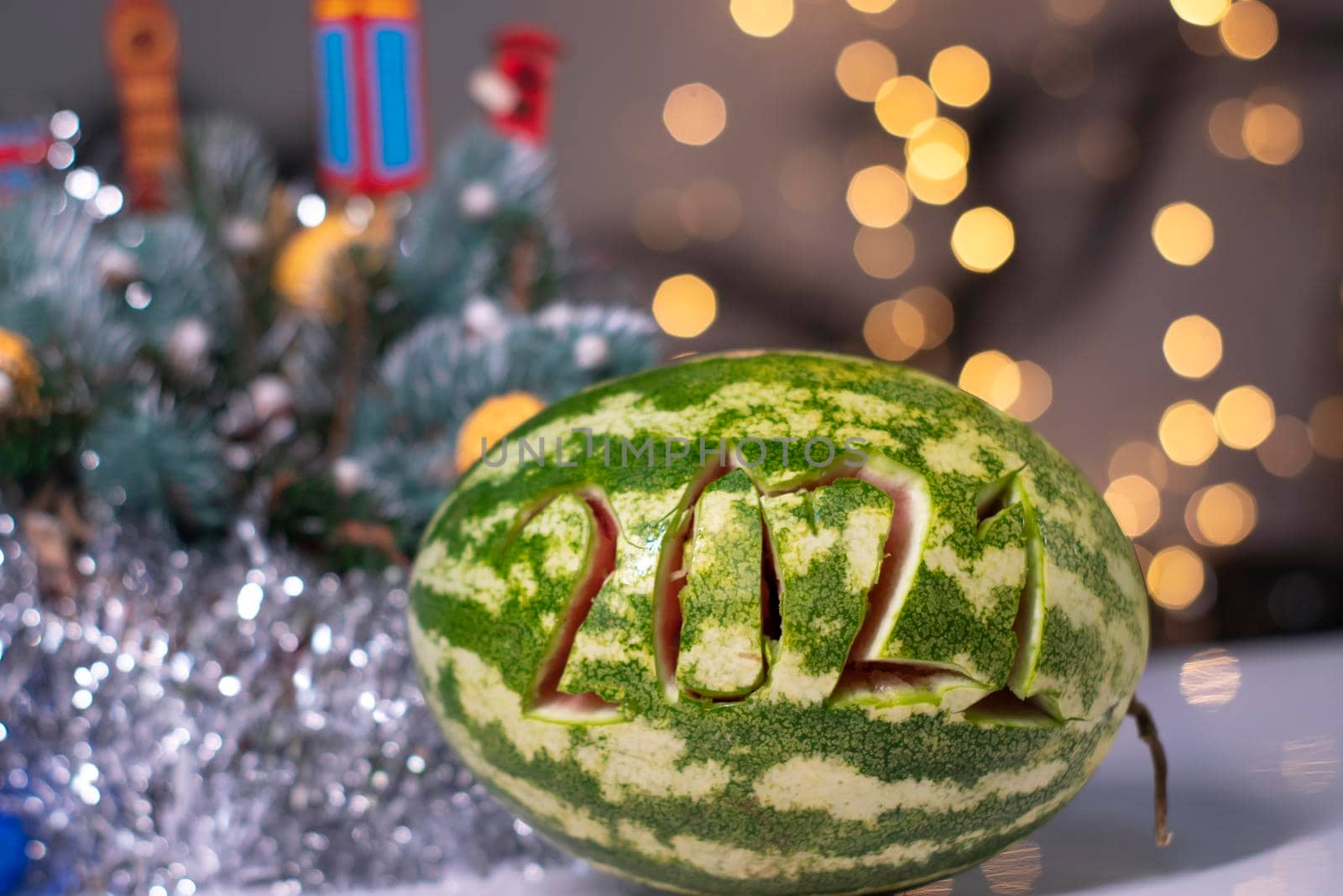 watermelon with 2021 carved number next to new year decorations. christmas theme.