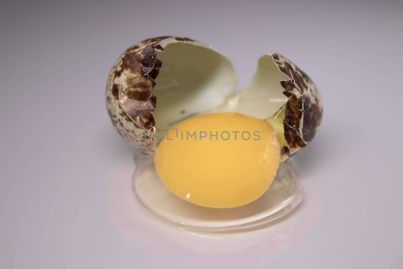 broken Quail egg isolated on white background with leaking white and yolk. healthy raw food.