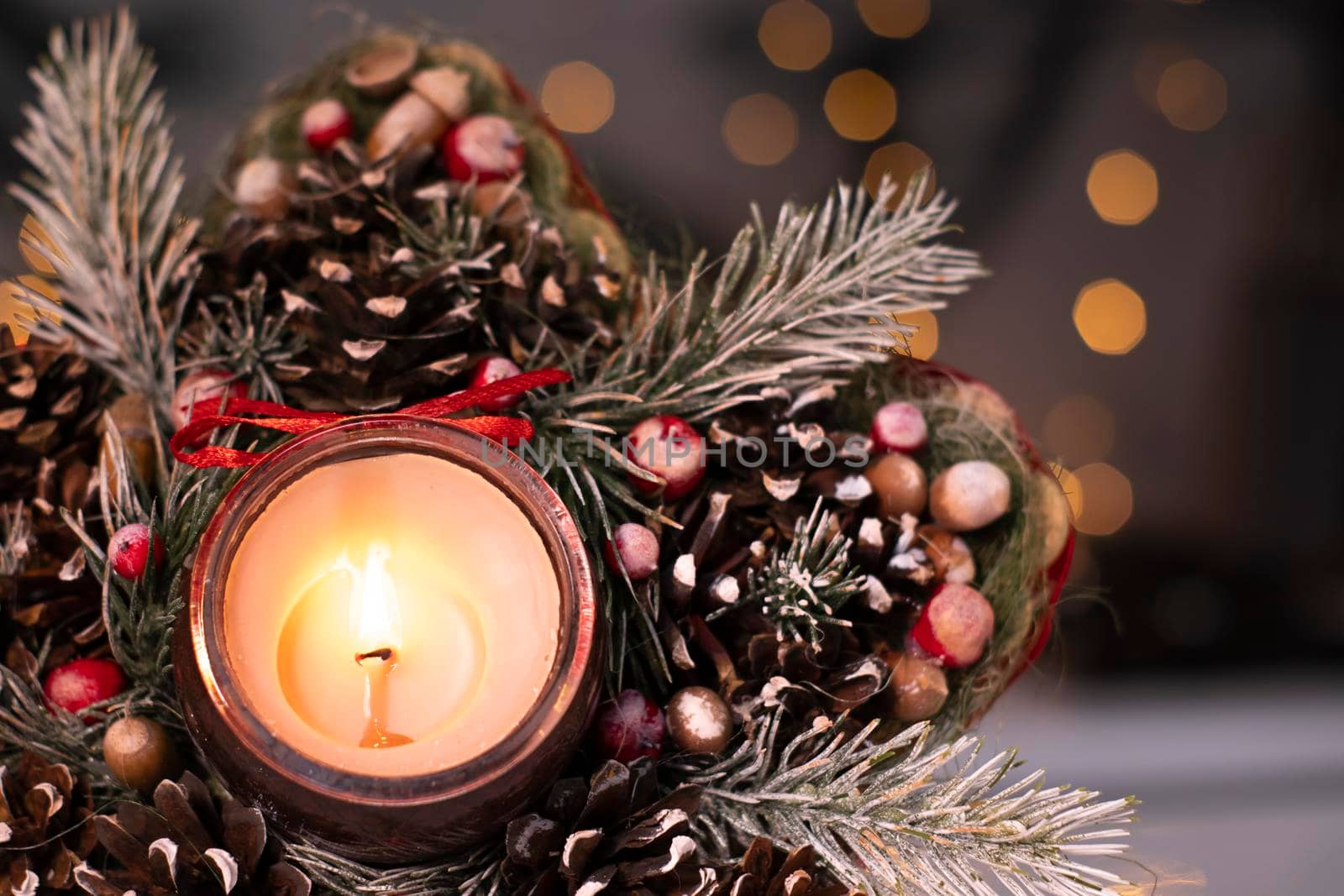 Christmas decor star-shaped made of tree branch with new years toys on it and a candle in it.