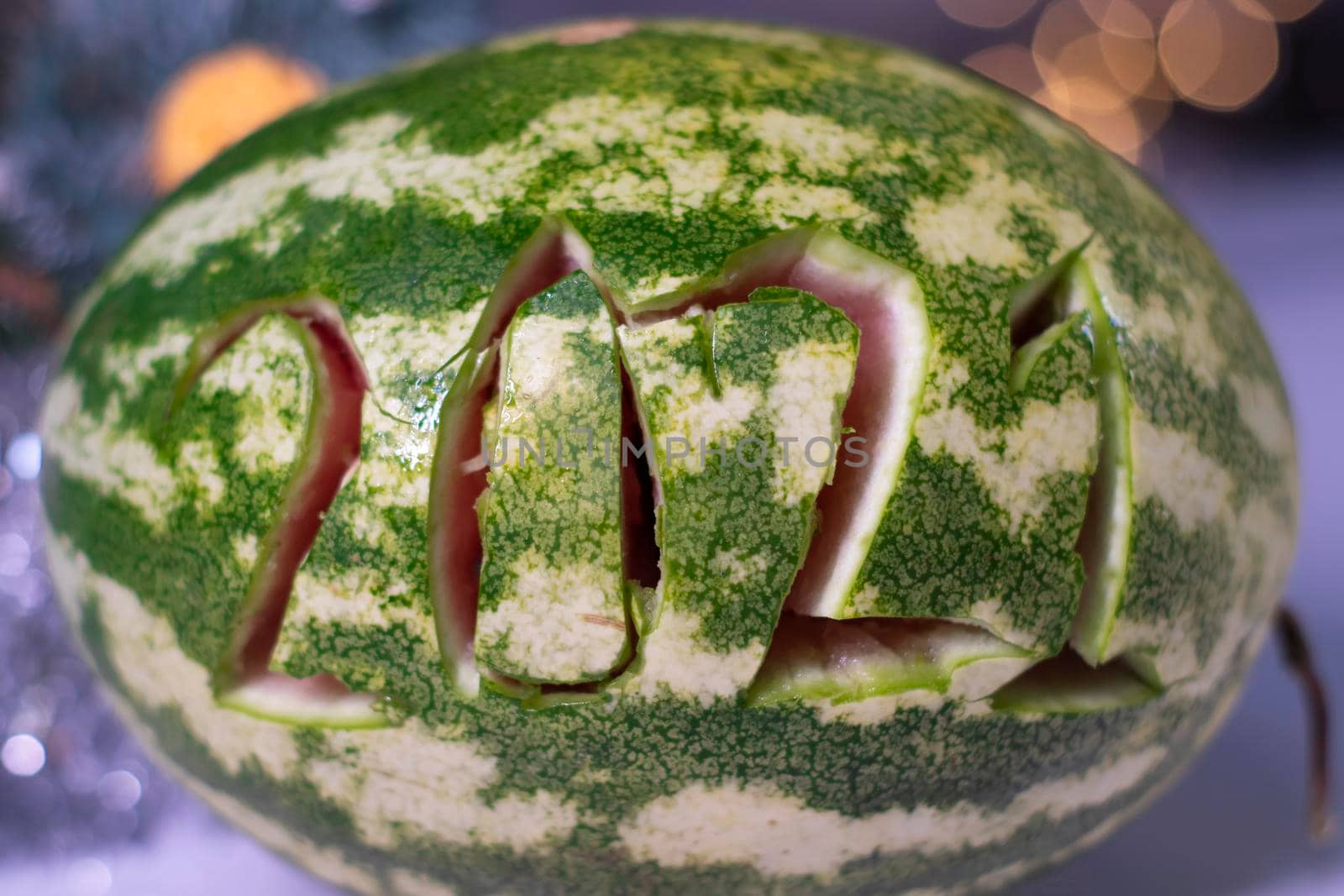 watermelon with 2021 carved number next to new year decorations. christmas theme by oliavesna