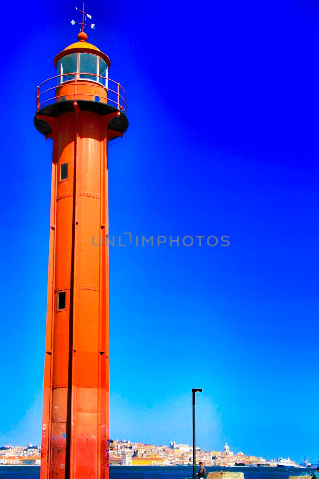Red lighthouse in the port of Almada village in Lisbon on a sunny day of winter.