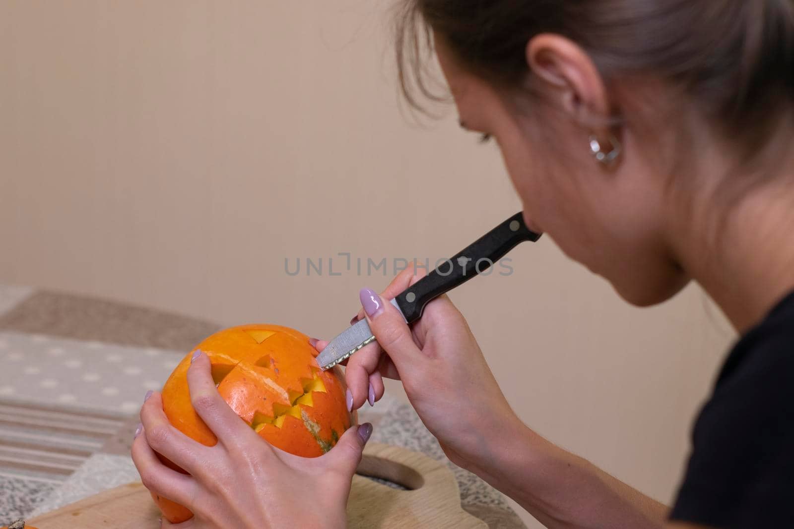 the process of making a Halloween pumpkin. cutting out the mouth by brunette girl. horror theme and Hallowe'en by oliavesna