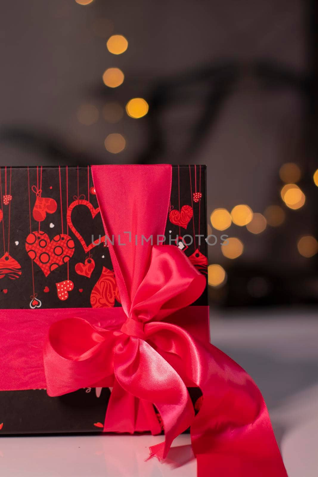 black with hearts gift box with pink ribbon bow on gold bokeh background by oliavesna
