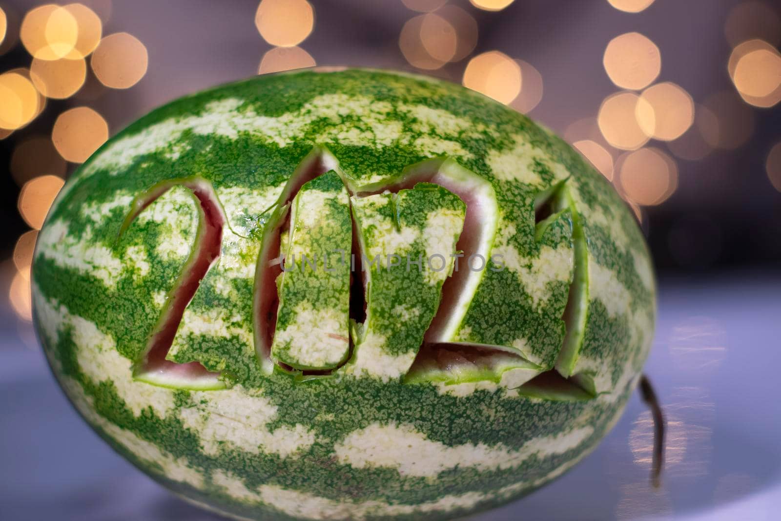 watermelon with 2021 carved number next to new year decorations. christmas theme by oliavesna