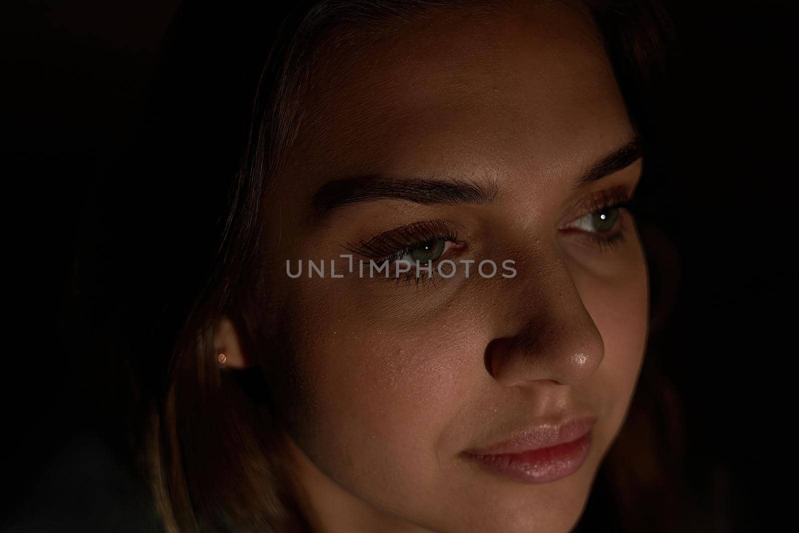 Facial portrait of a young beautiful girl with long dark hair. Low key woman portrait