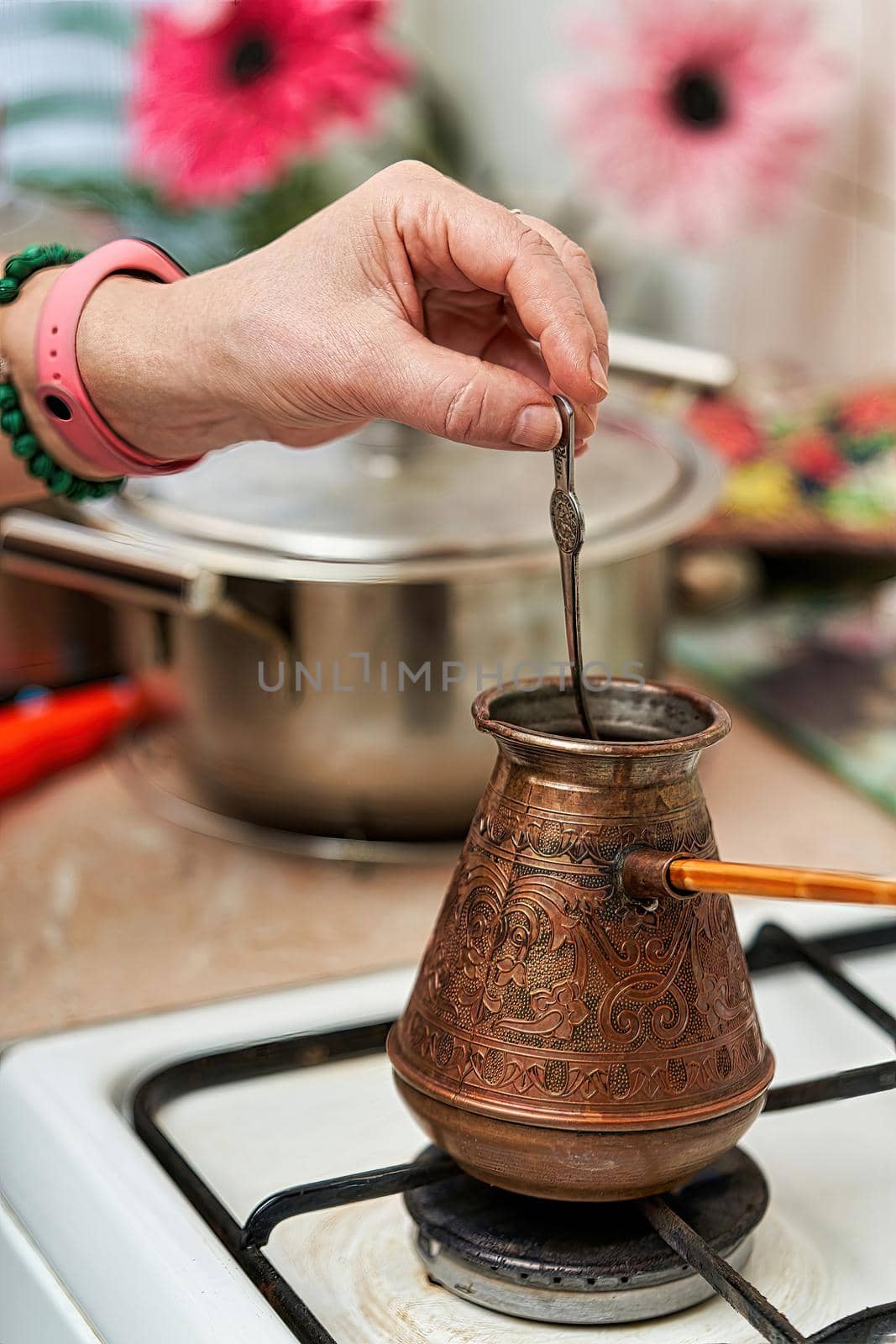 Cooking black coffee in a copper cezve on a gas stove in the kitchen at home. Close up