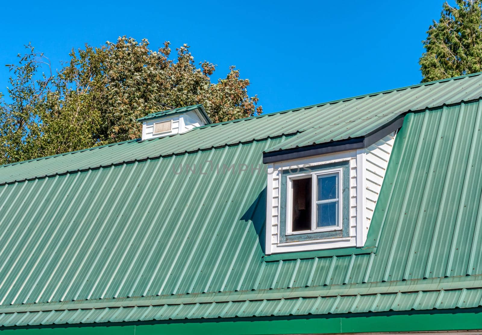 The window on green roof of a farm barn.