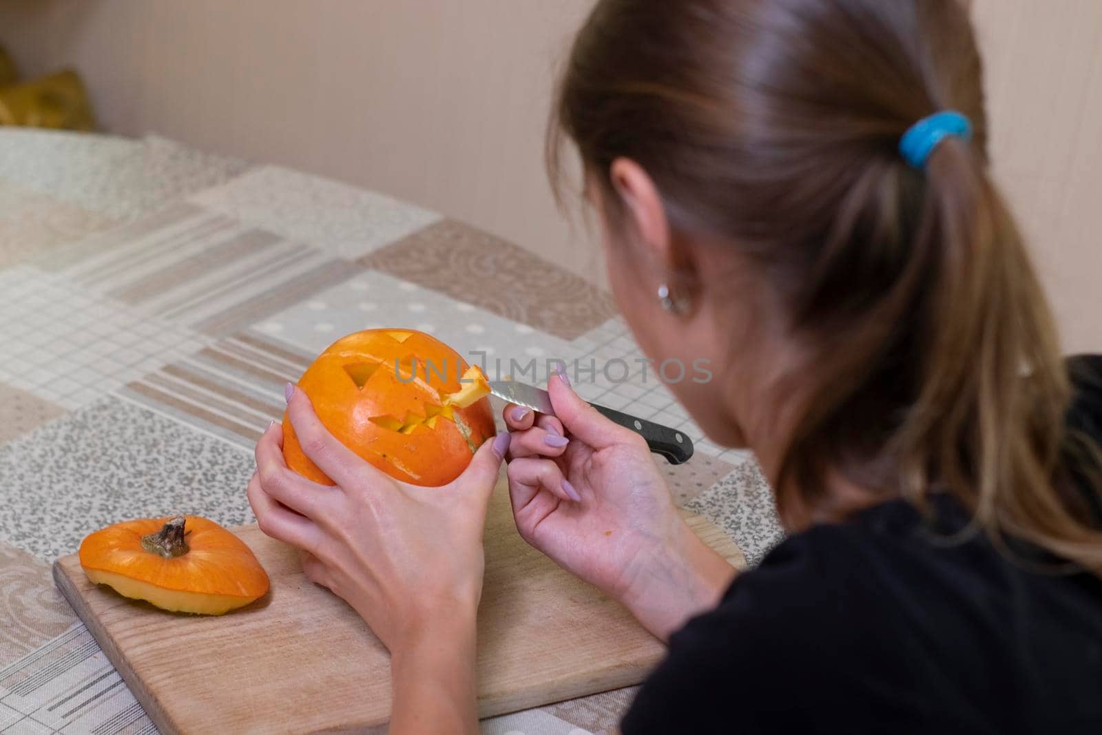 the process of making a Halloween pumpkin. cutting out the mouth by brunette girl. horror theme and Hallowe'en.