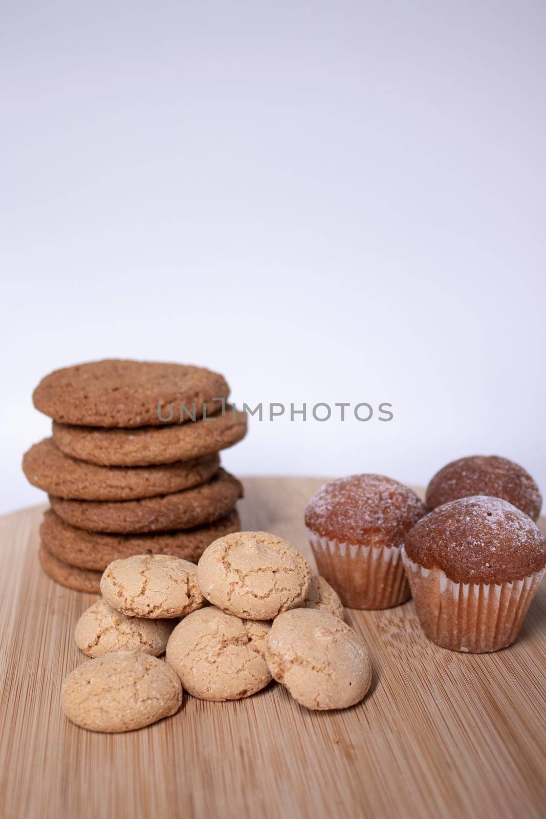 muffins, almond amaretti and oat cookies on wooden stand board. sweet bakery concept by oliavesna