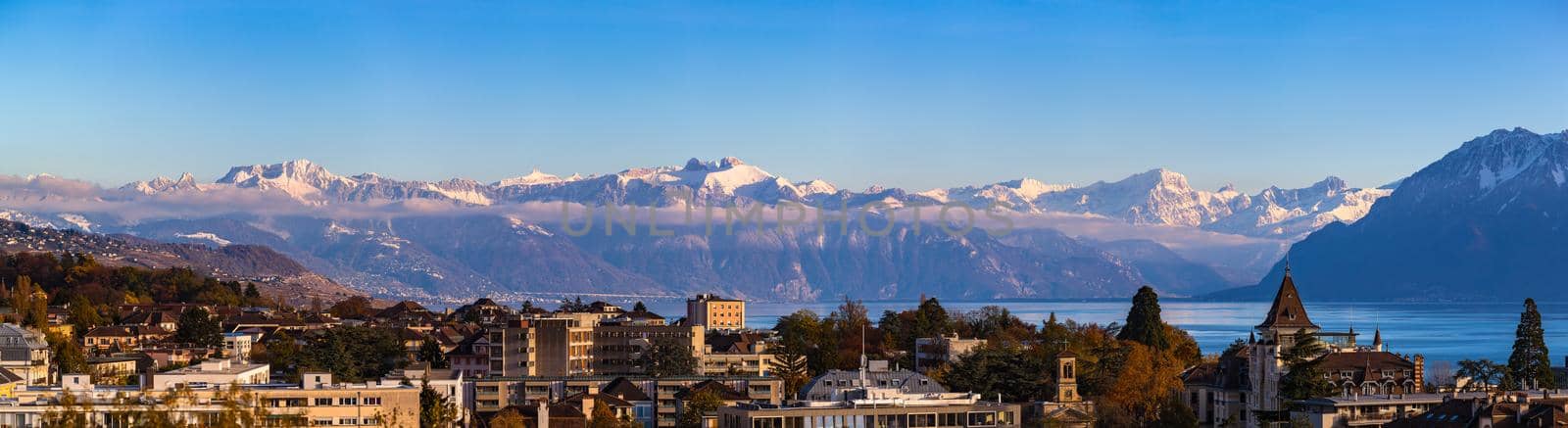 Stunning aerial panorama view of Lausanne cityscape with Lake Geneva (Lake Leman) and snow convered French Alps in background on a sunny autumn day with blue sky cloud, Canton of Vaud, Switzerland