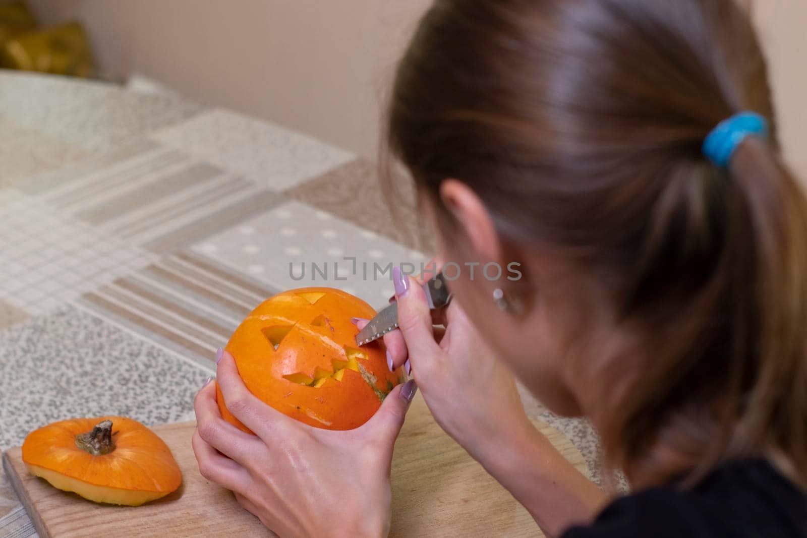 the process of making a Halloween pumpkin. cutting out the mouth by brunette girl. horror theme and Hallowe'en.