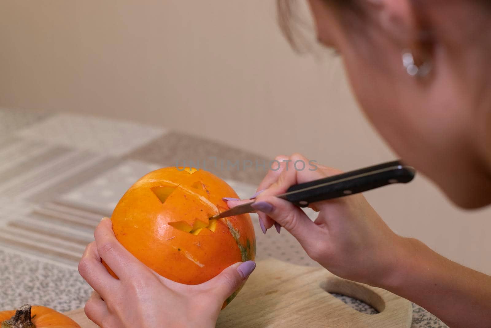 the process of making a Halloween pumpkin. cutting out the mouth by brunette girl. horror theme and Hallowe'en by oliavesna