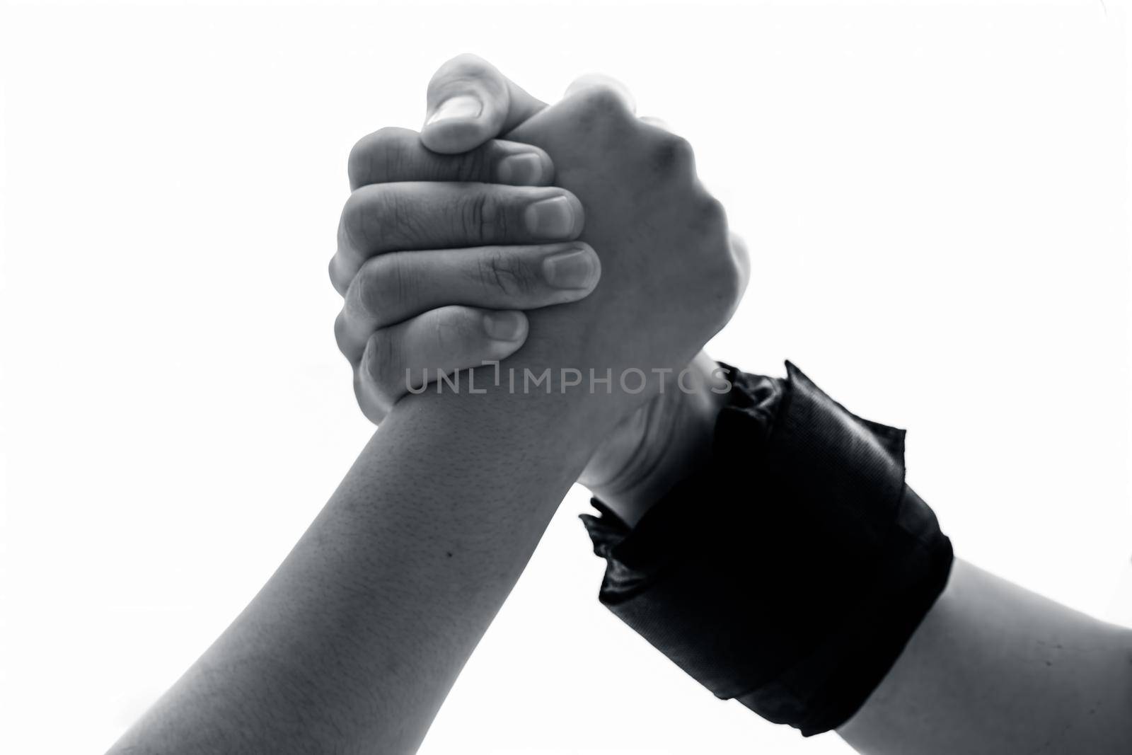 Male hand wearing black colored wrist weights and helping the other female hand isolated on white.Concept of togetherness and teamwork. by mirzamlk