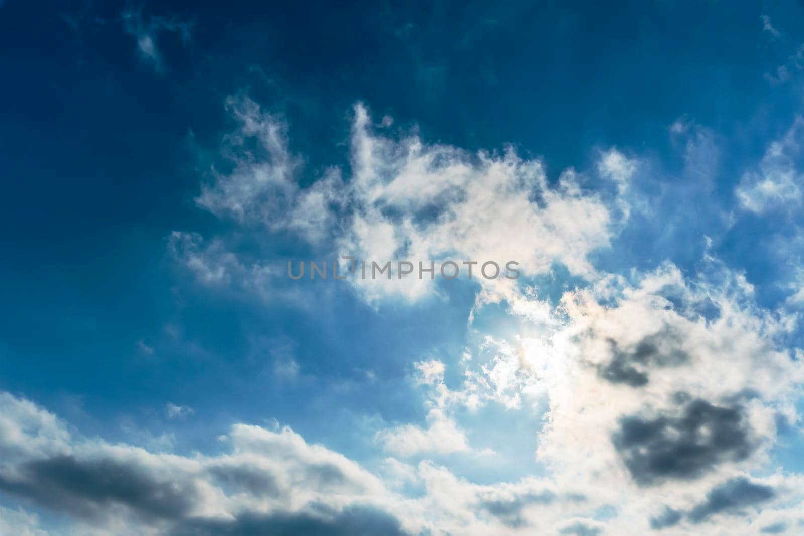 The rays of the sun break through the clouds.Blue sky with white feather clouds. Panoramic view of the blue sky with clouds in motion.Nice weather with clear skies. Panorama of the sky in motion by YevgeniySam