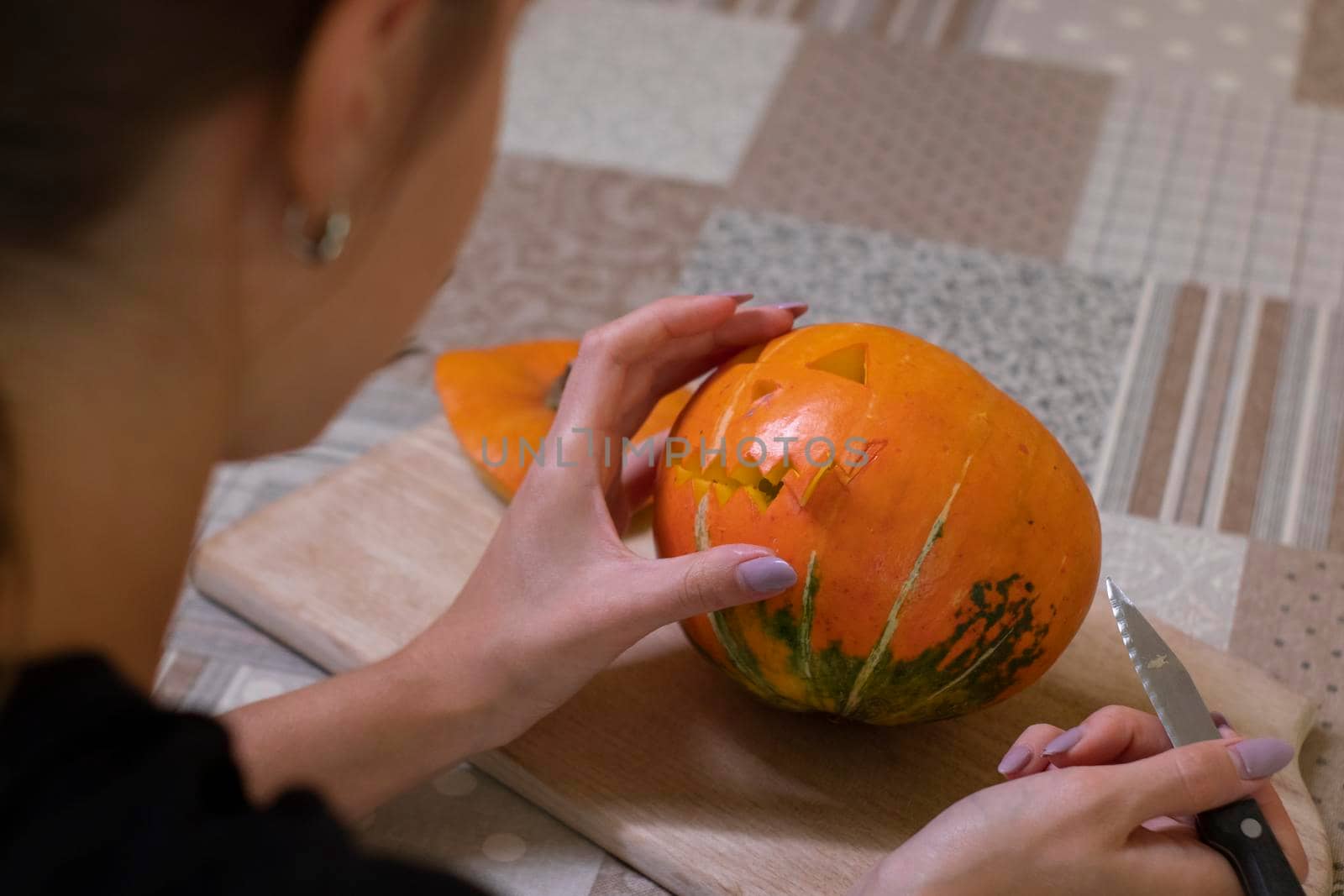 the process of making a Halloween pumpkin. cutting out the mouth by brunette girl. horror theme and Hallowe'en.